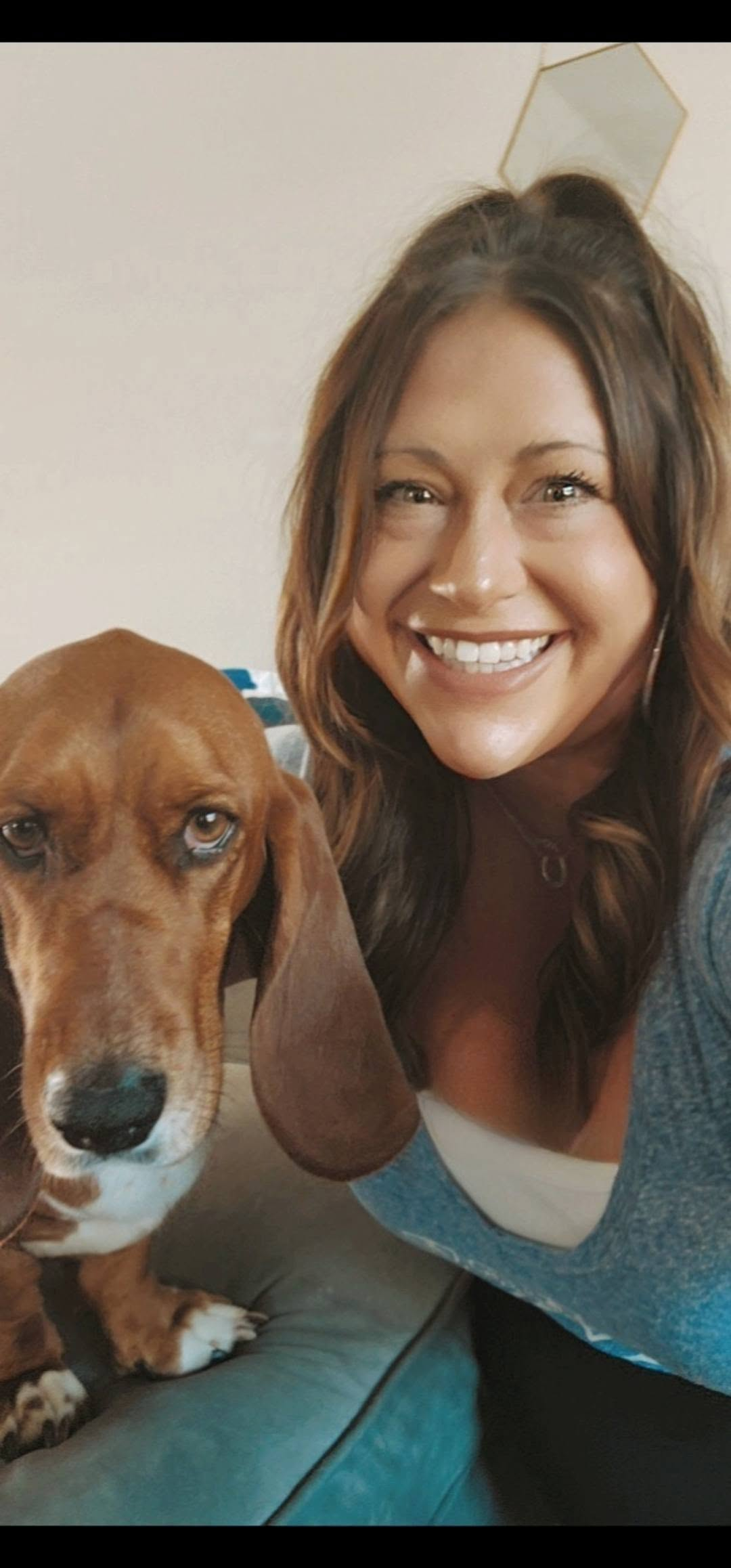 Julie with a basset hound on a teal couch