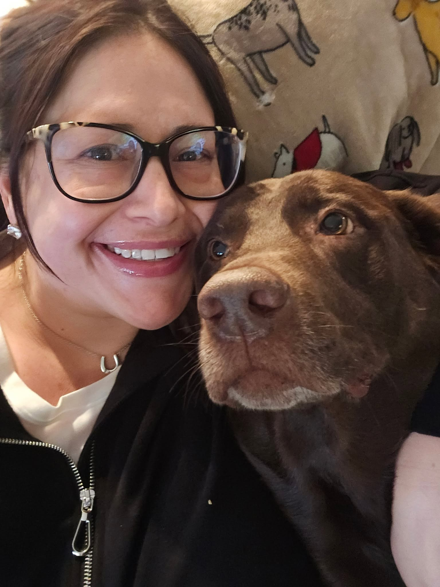 Julie with a chocolate lab leaning in close