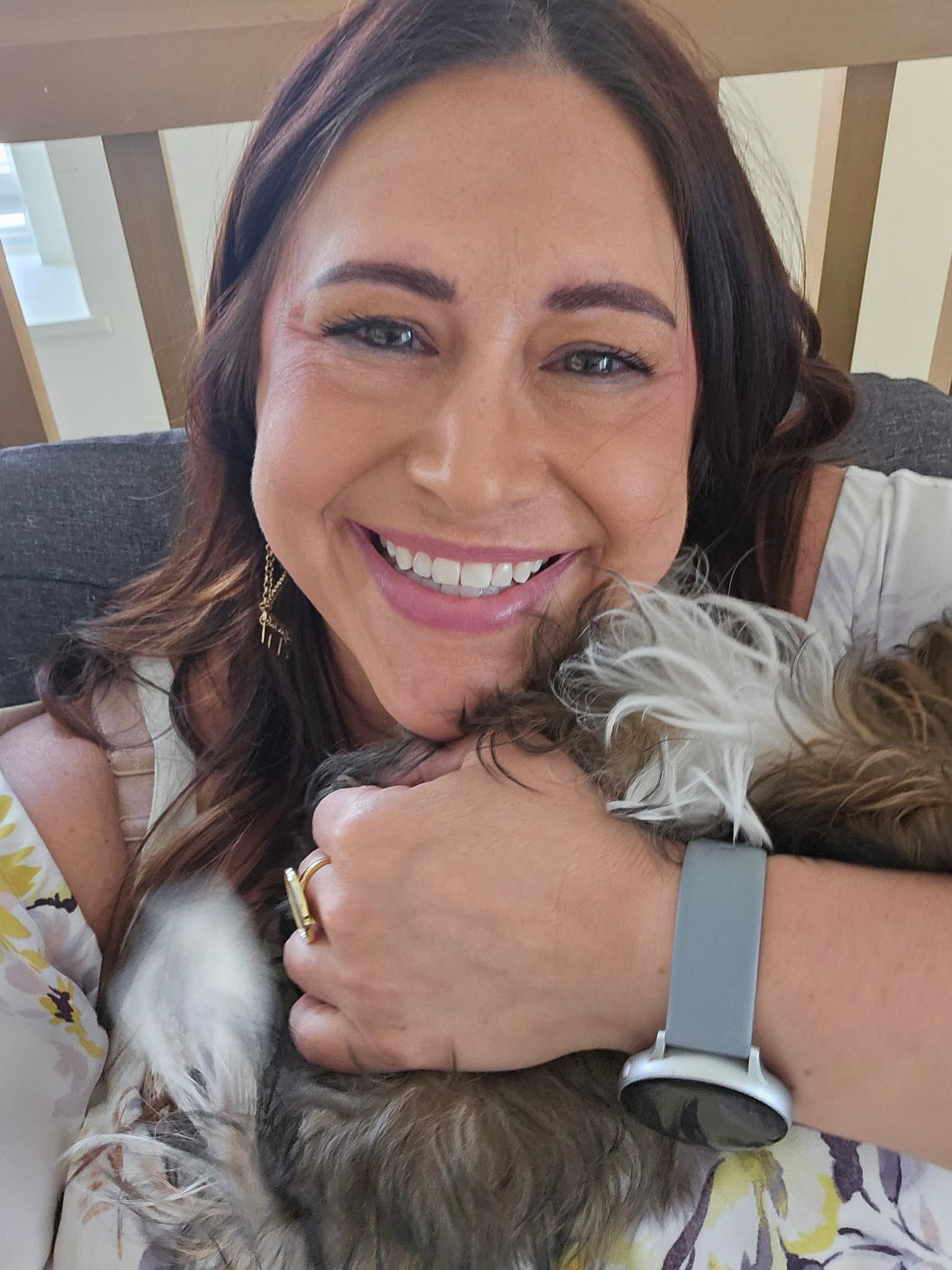 Julie hugging a small terrier on the couch